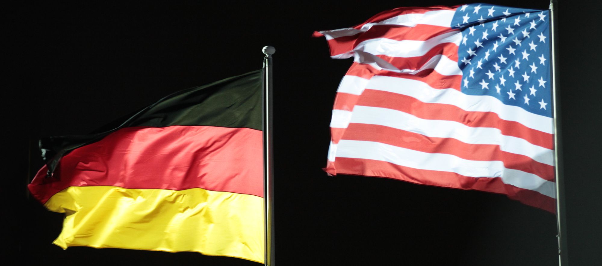 Image with black background and Germany and USA flags